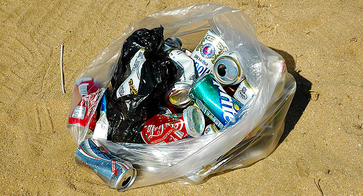 Bolsa de basura con latas en la playa