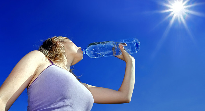 Chica bebe agua de una botella de plastico